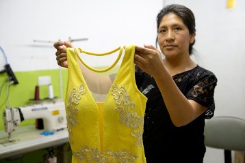 Nancy Salva, 41 Jahre, zeigt stolz ein Festkleid aus ihrer eigenen Kreation, das sie im Laden vor ihrer Schneiderwerkstatt verkauft