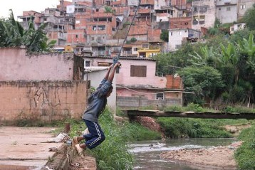 Jungen schwingen sich an einem Seil über einem zur Kloake verkommenen Bach in der Favela Jardim Paraná im Distrikt Brasilandia im Norden von São Paulo. In Regenzeiten tritt der Bach regelmäßig über das Ufer, so dass die Gegend nur von den ärmsten Familien bewohnt wird.