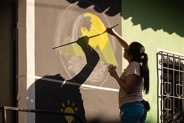 Eine Leiterinnen beim Malen eines Wandbildes an das neue Jugendzentrum.