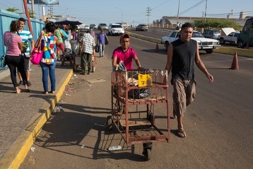 Vicente González schiebt seinen Handwagen zum Busbahnhof, in der Nähe vom Markt "Las pulgas" in Maracaibo. Neben ihm geht Orlando Machado von JOC Venezuela