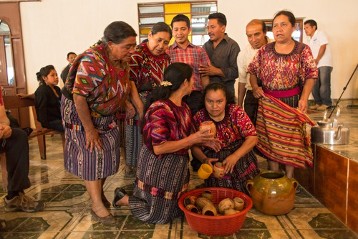 Empfang im Mayadorf Chontalá -Begrüßung in der Kapelle. Frauen in der typischen Tracht des Quiché servieren Atól de Mais.