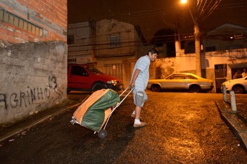 Cesar Coila, 45 Jahre, macht sich früh Morgens mit einer Tasche voller Kleider auf den Weg zum informellen Markt im Zentrum von Sao Paulo, Cangaíba