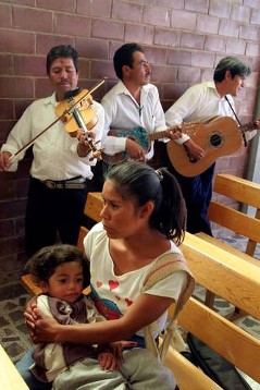 Musikanten spielen in der Pfarrkirche in Tixqui (Gemeinde Cardonal), während eine junge Mutter den Gottesdienst verfolgt.