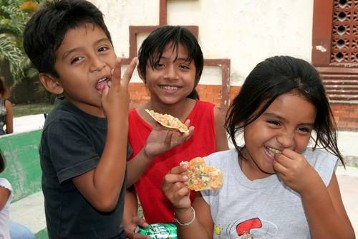 Kinder essen Maisfladen nach dem Gottesdienst vor der Pfarrkirche von San Benito