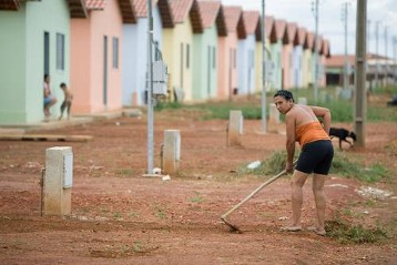 Eine Frau harkt vor ihrem Reihenhaus in der Siedlung Real Conquista am Stadtrand von Goiânia